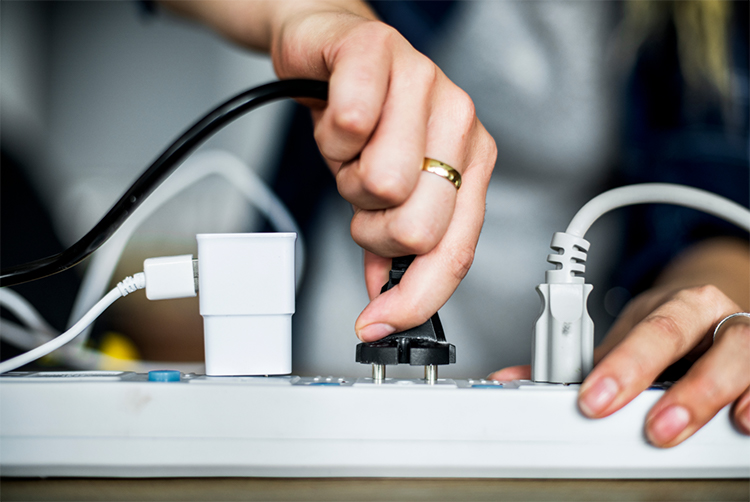 A person removes a device from a power strip to avoid energy waste from vampire devices