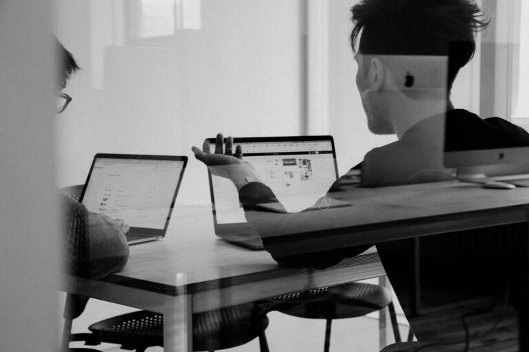 Men conversing with laptops open